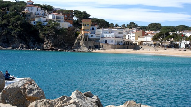 A coastal town with buildings on a hillside overlooking a beach. - Hotel Llafranch (Palafrugell)
