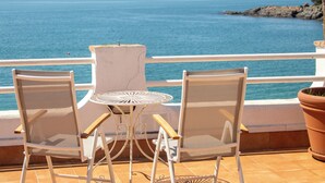 A terrace with two chairs and a table, overlooking a calm sea and rocky coastline. - Hotel Llafranch (Palafrugell)