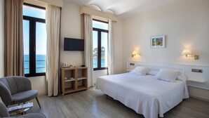 A hotel room with a large bed, a TV, a desk, and a chair. - Hotel Llafranch (Palafrugell)