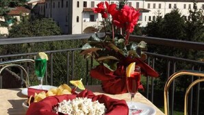 A table set with a red cloth, a bowl of popcorn, a glass of green drink, and a plate with a red flower arrangement. - Hotel PRime già Hotel Piccolo Ritz (Pistoia)