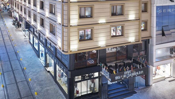 Un hôtel à plusieurs étages, doté d’un design moderne, avec une entrée imposante agrémentée d’une enseigne et une façade bien éclairée.