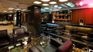 Un hall d’hôtel avec des canapés en cuir, un coin bar avec des tabourets et un sol recouvert de moquette.