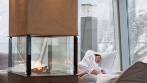 Una sala de estar moderna con una chimenea de vidrio, un sofá y una persona descansando en el diván.