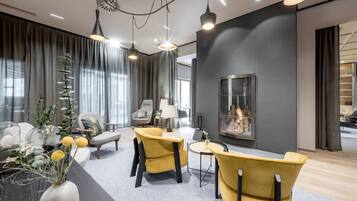 A modern living room with a fireplace, comfortable seating, and a large window with curtains.