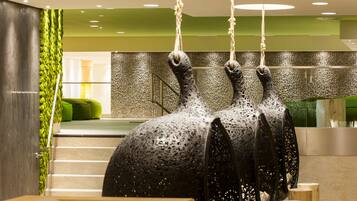 A modern interior with a unique sculpture, a staircase, and a green accent wall.