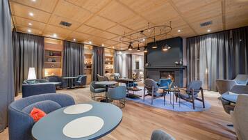 Un espace de détente moderne avec un plancher en bois, des tables rondes et des sièges confortables.
