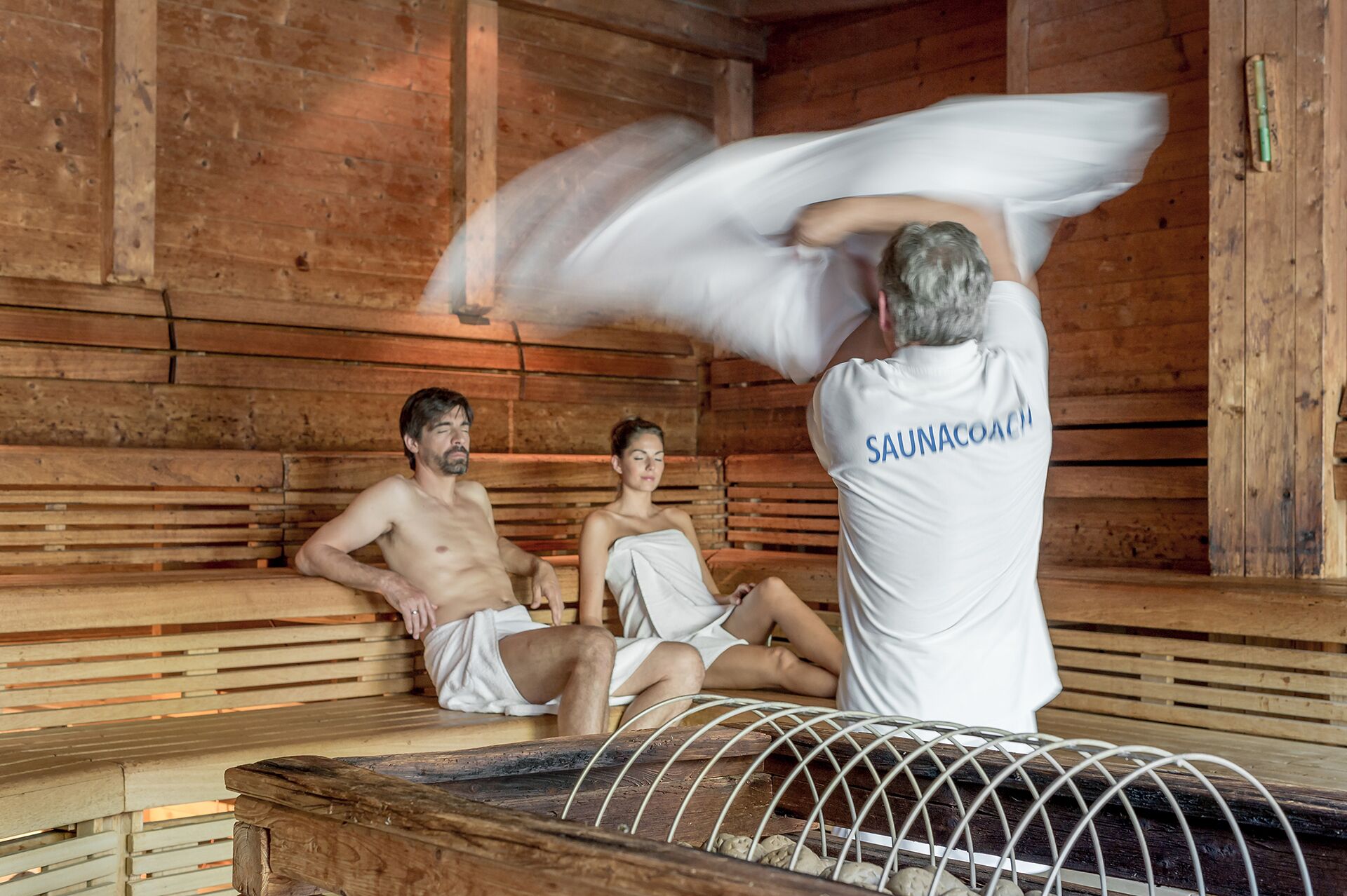 Eine Sauna mit Holzbänken und einem Metallrostboden.