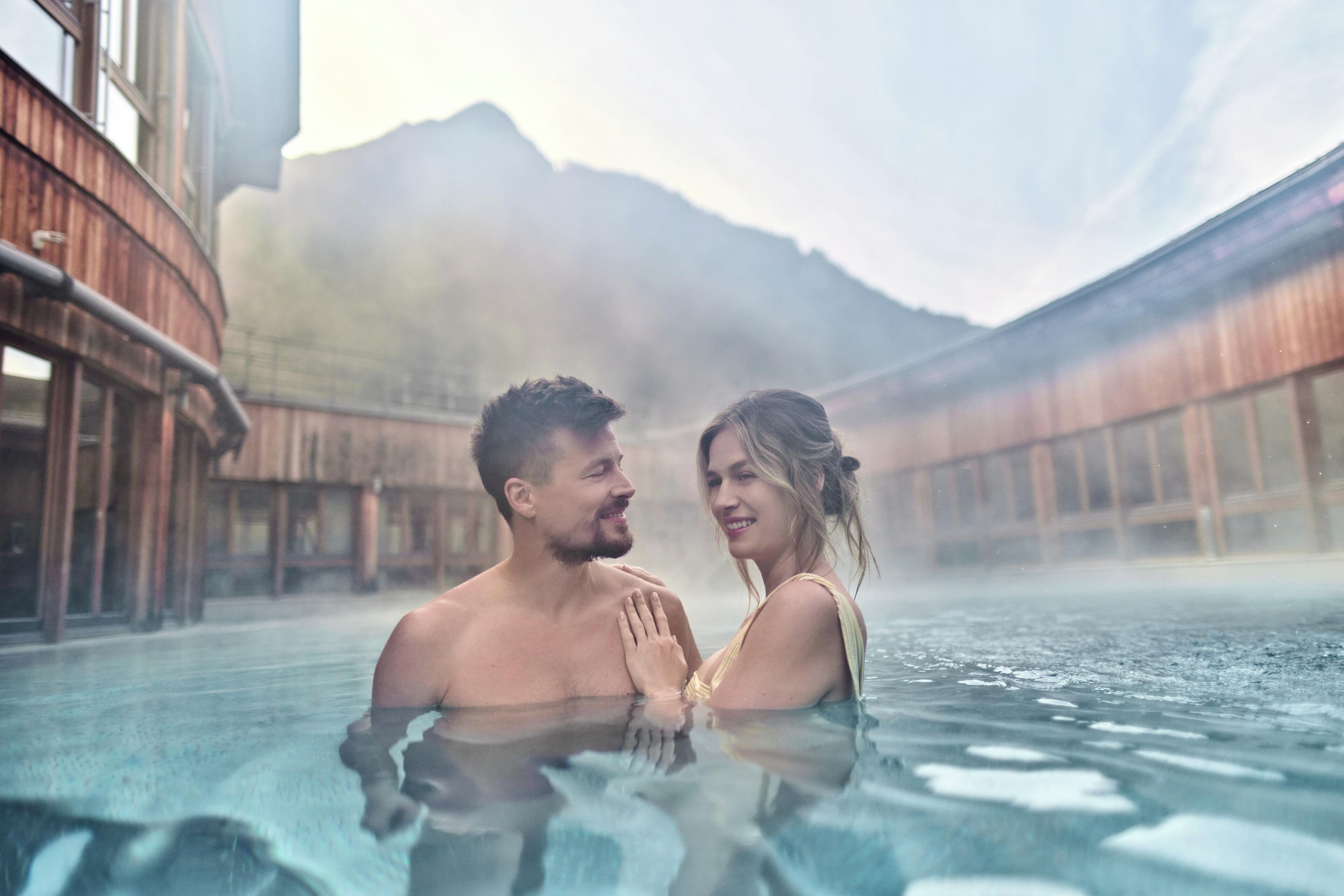 A couple in a hot tub with a mountainous backdrop.