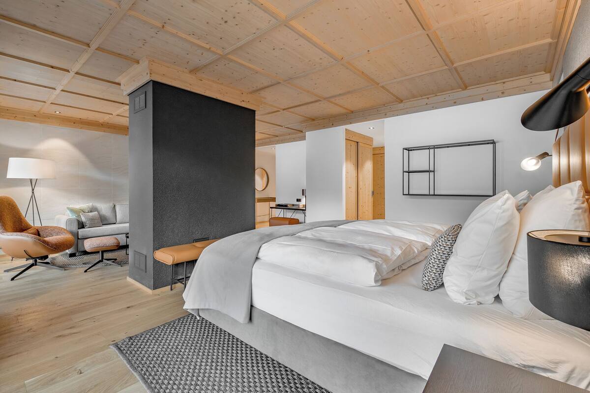 A modern bedroom with a large bed, a desk, and a chair.