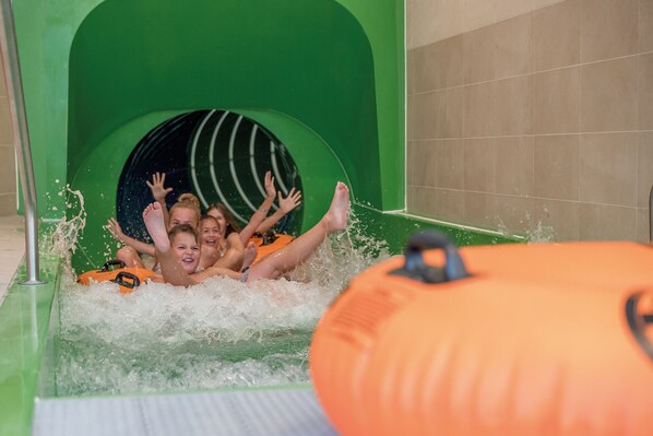A water slide with a green arch and a pool of water at the bottom.