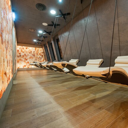 A row of massage chairs in a spa room with a wooden floor and stone wall.
