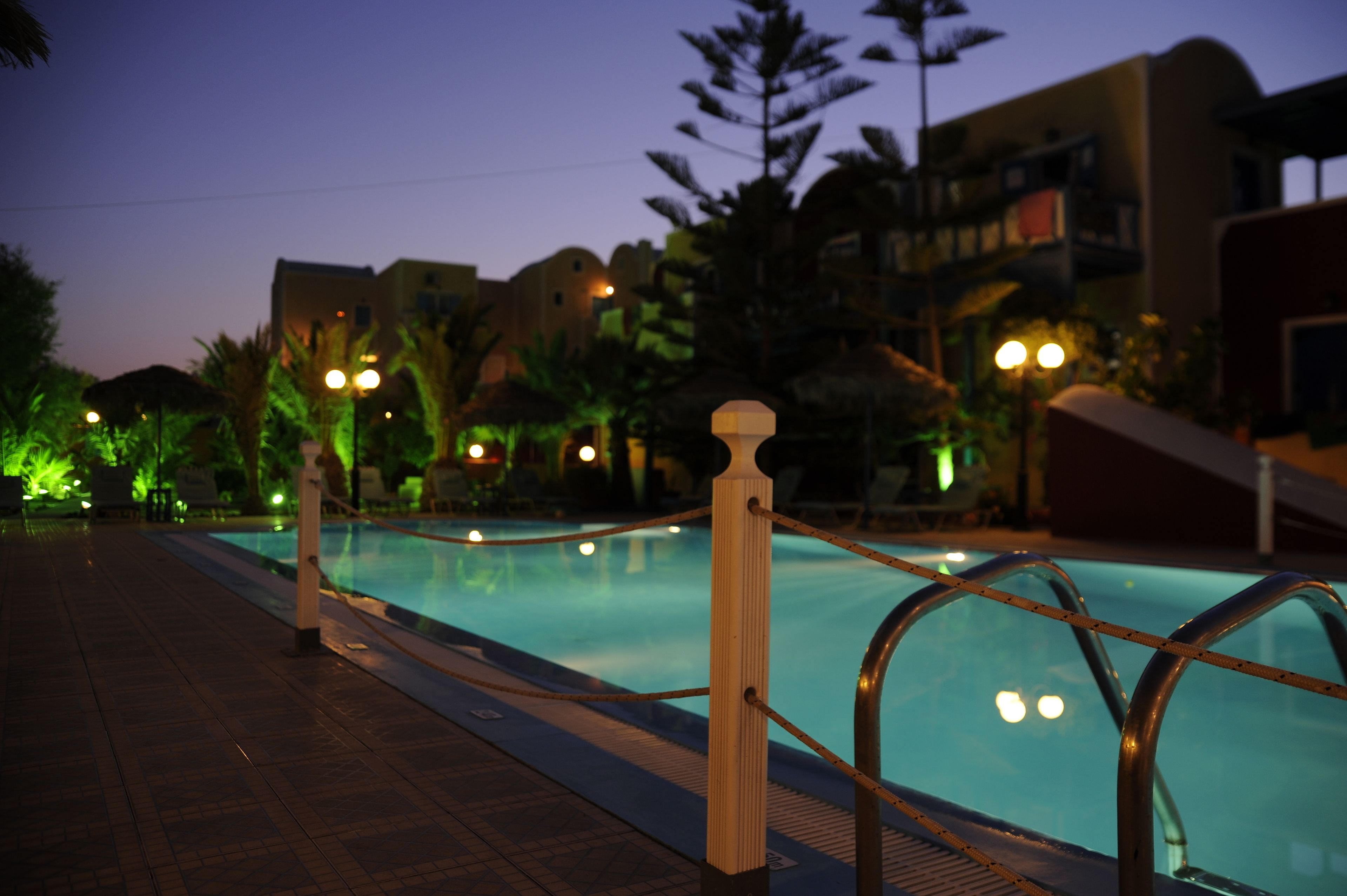 A swimming pool with a metal railing and a tiled walkway.