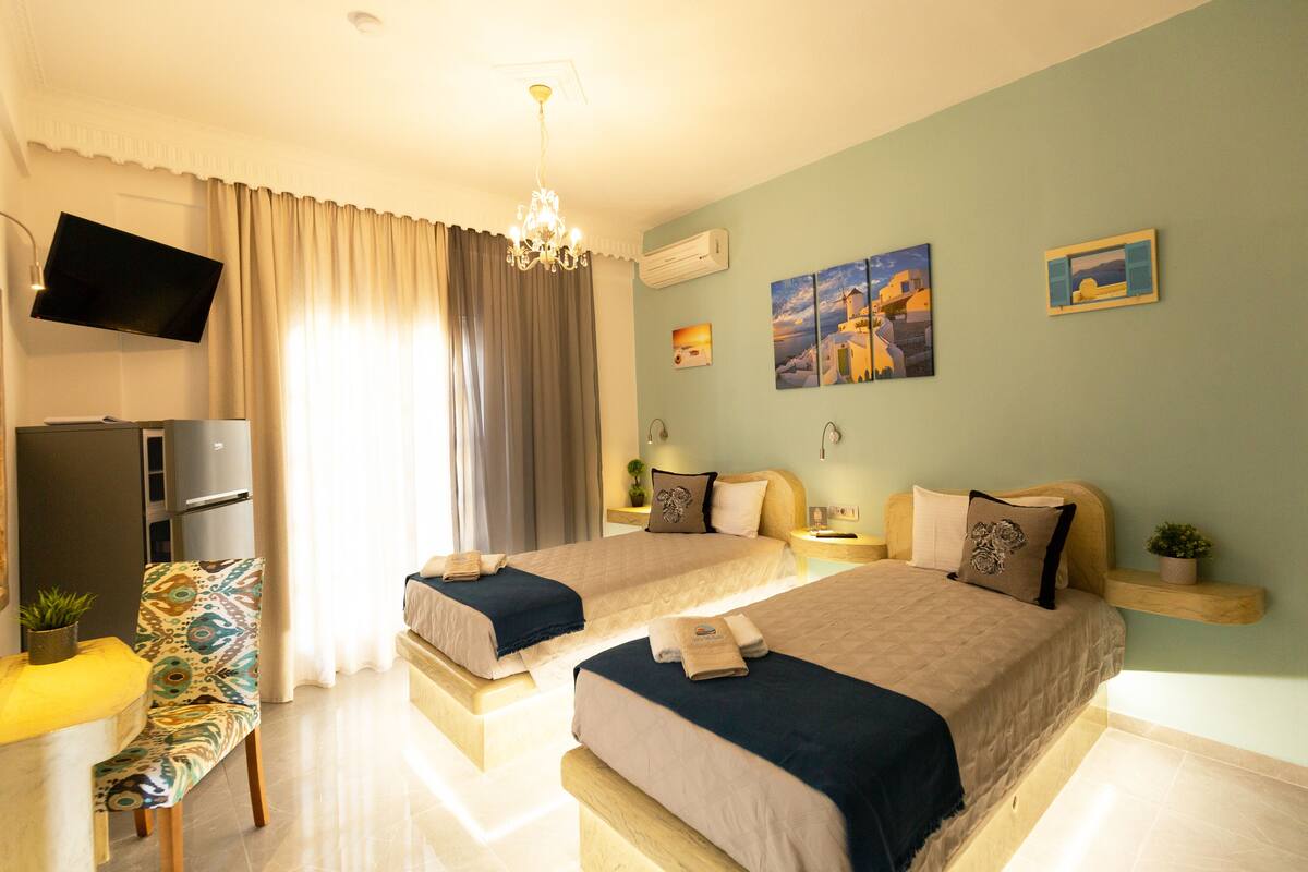 A hotel room with two beds, a TV, a desk, and a chair.