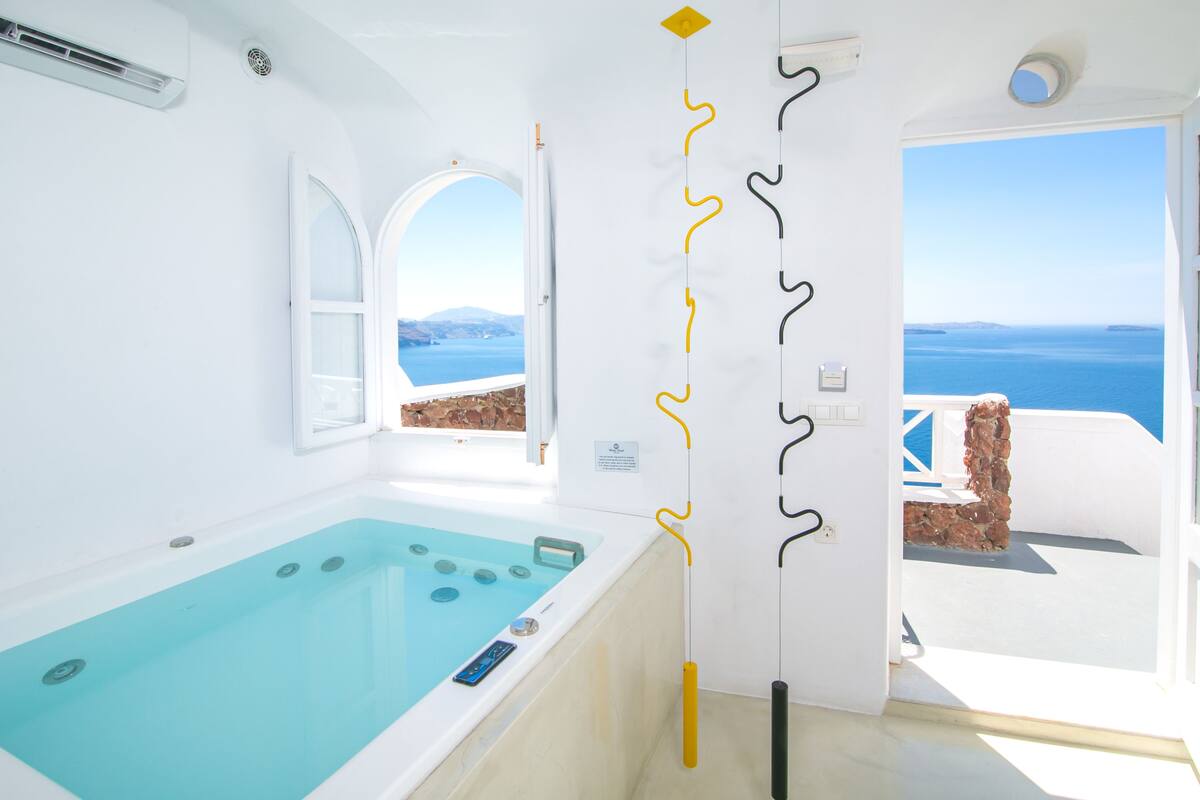Un bany modern amb banyera, vista al mar i una porta amb detalls decoratius.
