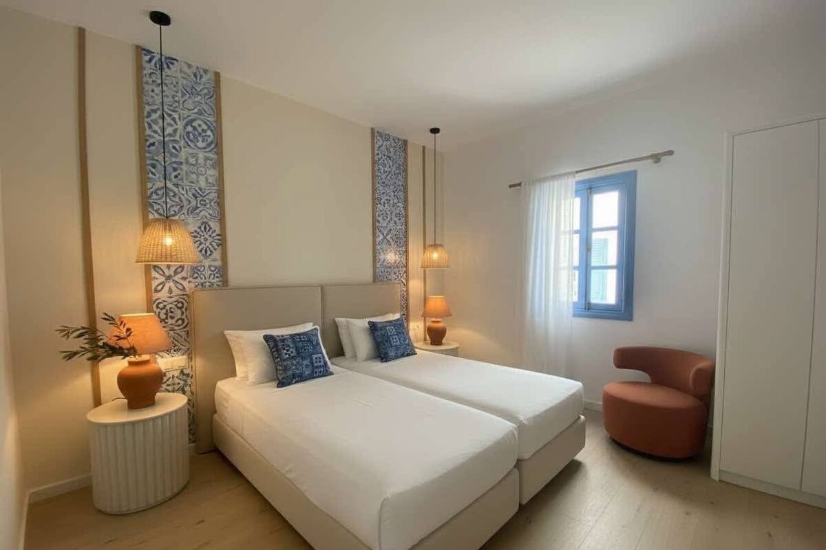 Habitació amb dos llits, una cadira i una finestra.