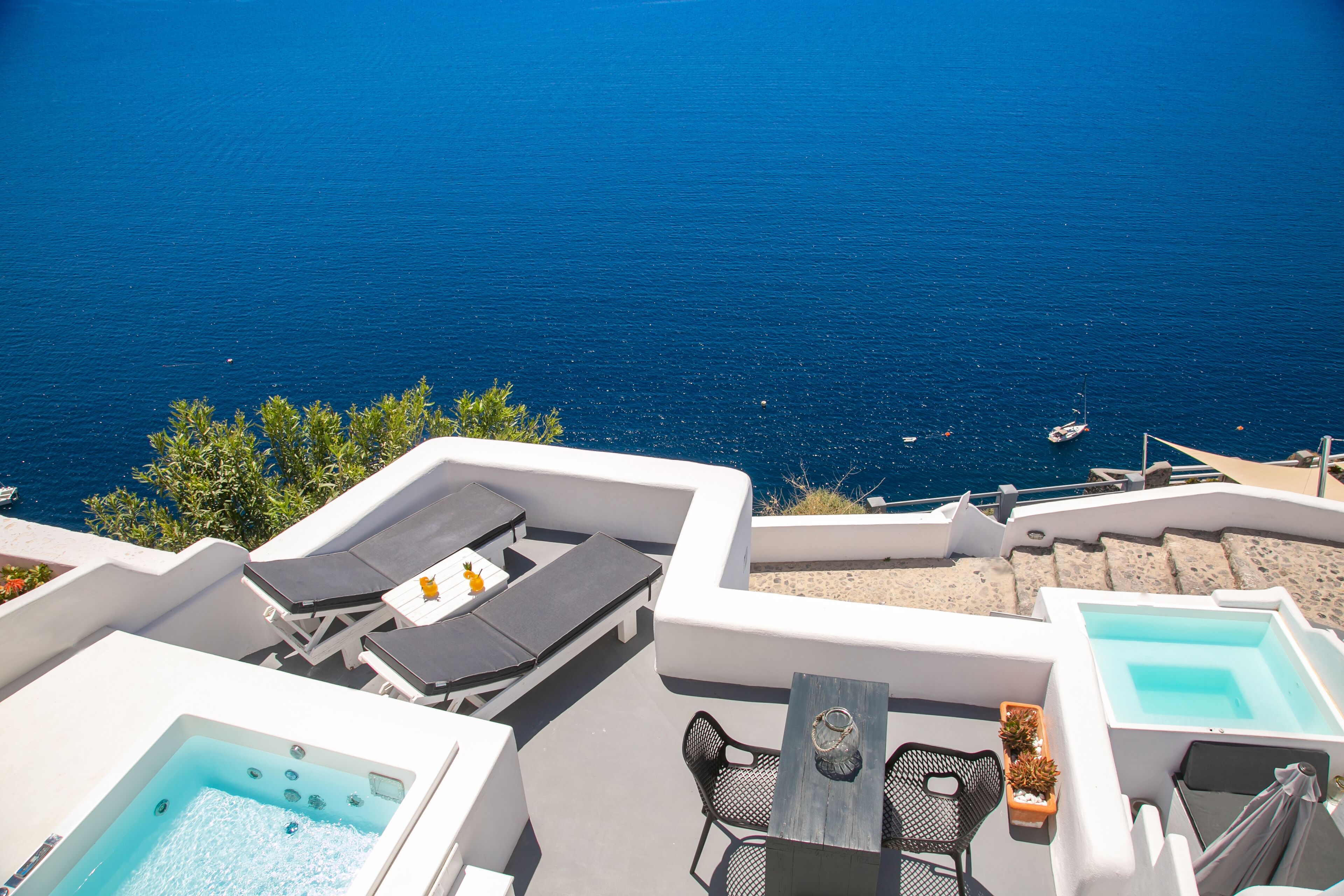 Une terrasse sur le toit avec une piscine, des chaises longues et une table offrant une vue sur la mer.