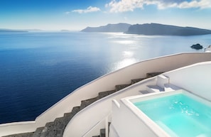 Vista de una piscina con una escalera que conduce a un balcón con vistas a una masa de agua y accidentes geográficos lejanos.