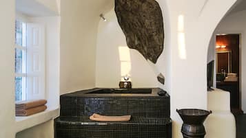 A bathroom with a large bathtub, a sink, and a towel rack.