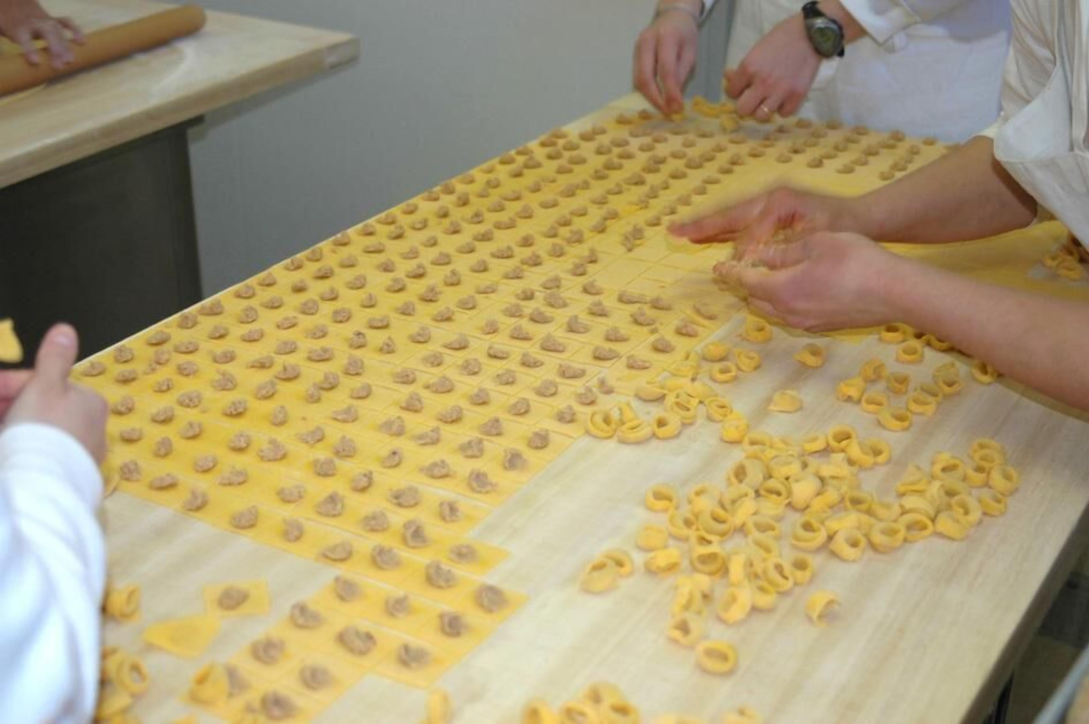 Een tafel waarop pastadeeg wordt uitgerold en in vormen gesneden.