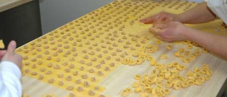 A table with pasta dough being rolled out and cut into shapes.