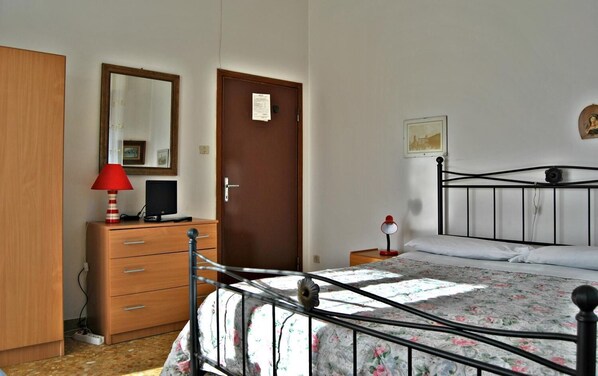 Une chambre à coucher avec un lit, une commode, un bureau, un miroir et une porte.