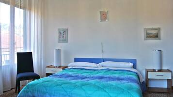 A bedroom with a bed, two bedside tables, a chair, and two wall-mounted lamps.