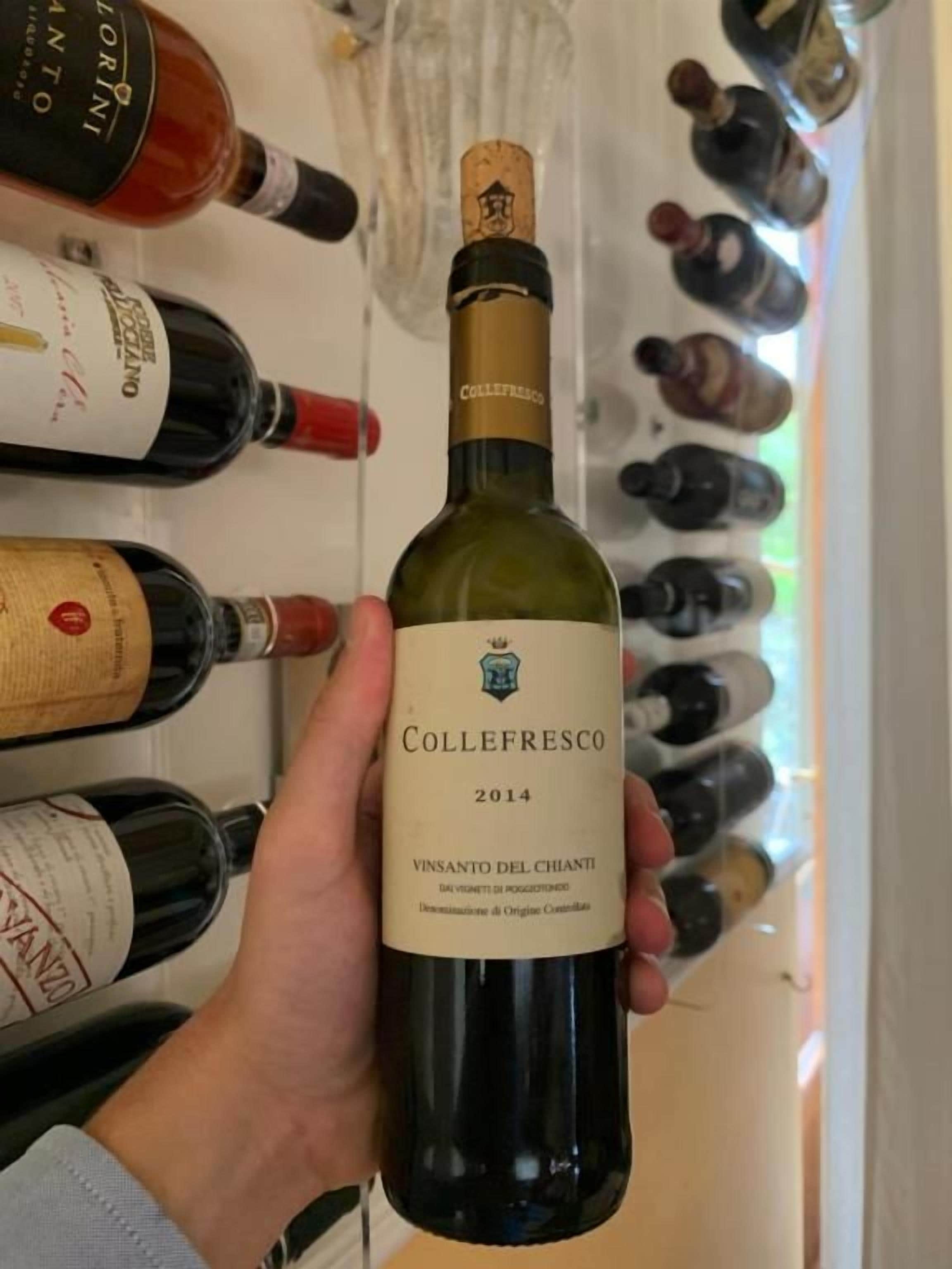 Una mano che tiene una bottiglia di vino con un'etichetta che riporta 'Collefresco 2014 Vinsanto del Chiantio'.