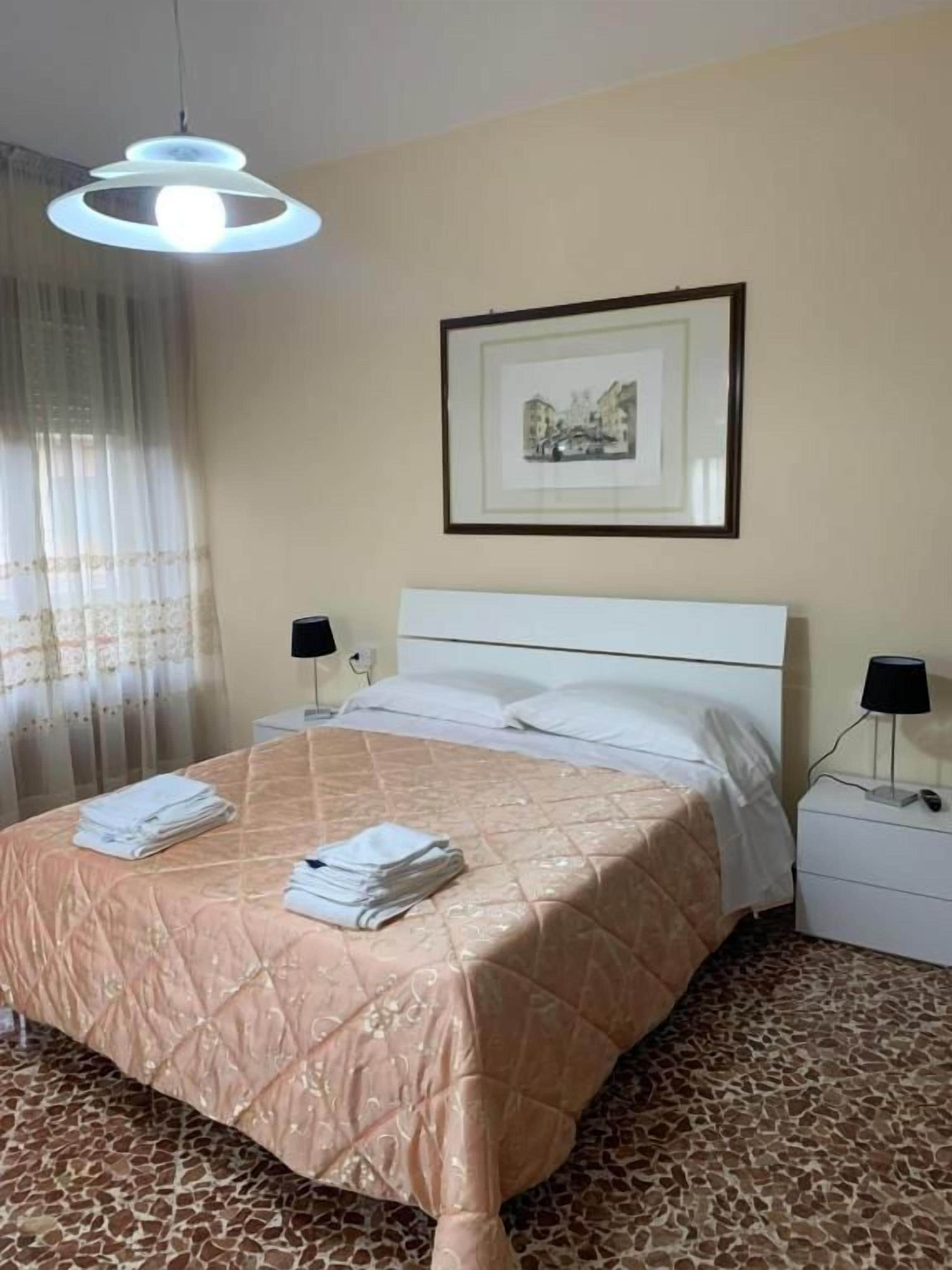 Een hotelkamer met een bed, een lijst met foto aan de muur en een nachtkastje met een lamp.