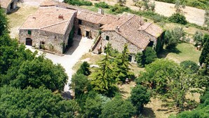 Un edificio de piedra con techo de tejas, rodeado de árboles y vegetación.