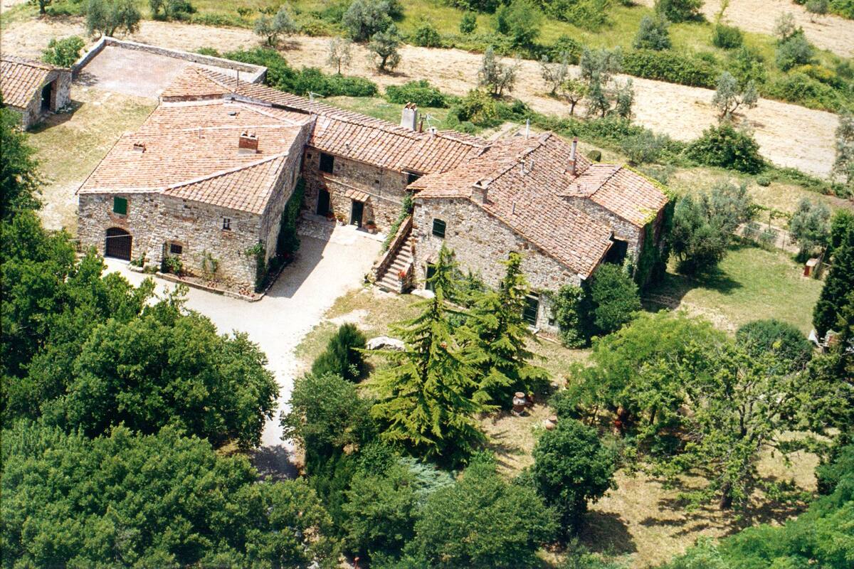 Edifici de pedra amb teulada aïllada, envoltat d'arbres i vegetació.
