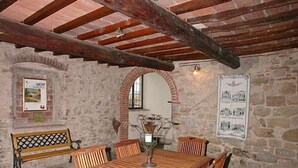 Una habitación rústica de piedra con una mesa y sillas de madera, un banco y un cartel en la pared.