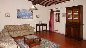 Una sala de estar acogedora con techo de madera, un sofá, una mesa de centro y un aparador.