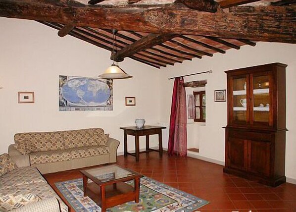 Una sala de estar acogedora con techo de madera, un sofá, una mesa de centro y un aparador.