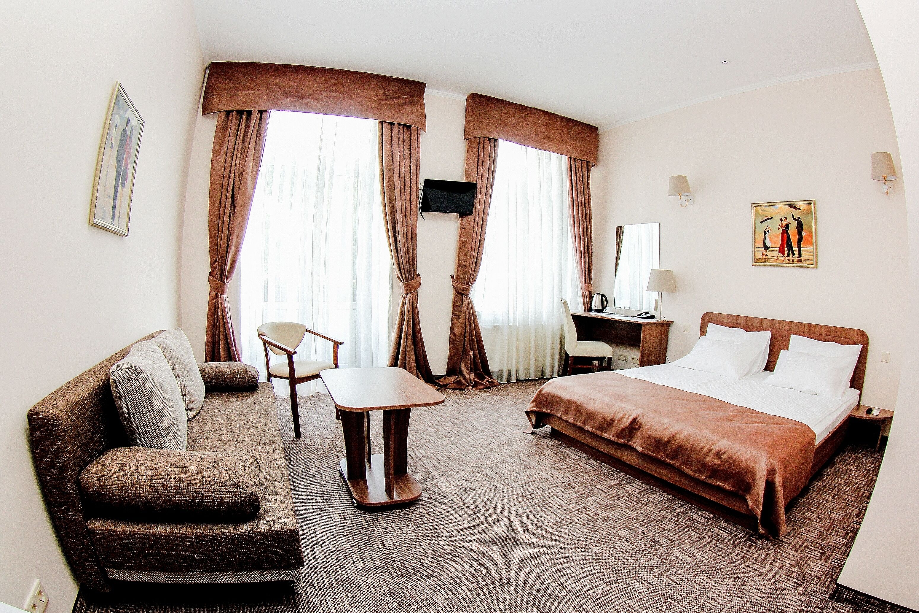A hotel room with a bed, a sofa, a desk, and a chair.