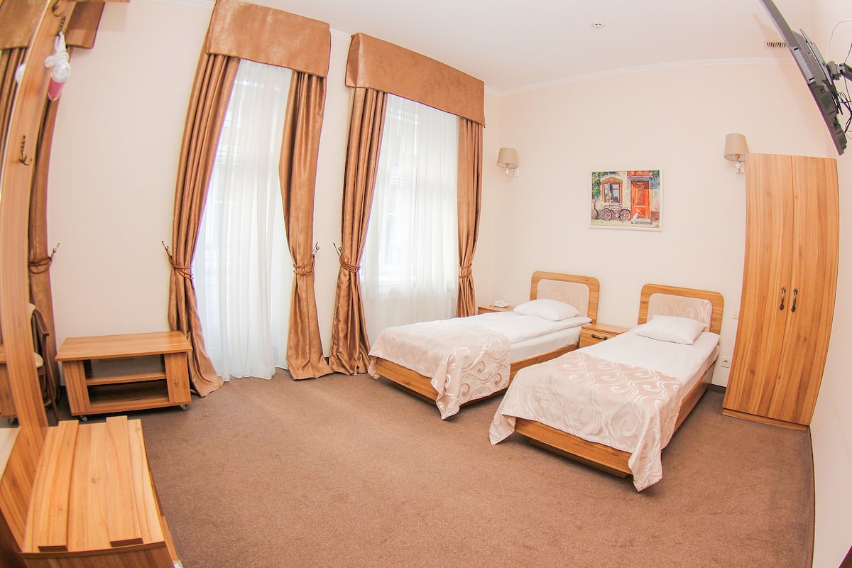 A room with two beds, a wooden desk, and a wardrobe.