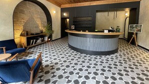 A reception area with a wooden ceiling, a stone wall, a reception desk, a blue sofa, and a patterned floor. - Hotel 52 (Odesa)
