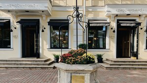 A building with a sign reading "restaurant" above the entrance. There is a wrought iron lamp post in front of the entrance, and a planter with flowers to the left. - Hotel 52 (Odesa)