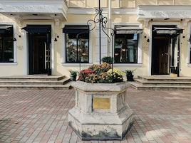 Un edificio con un letrero que dice “restaurante” sobre la entrada. Hay un farol de hierro forjado frente a la entrada, y una maceta con flores a la izquierda.