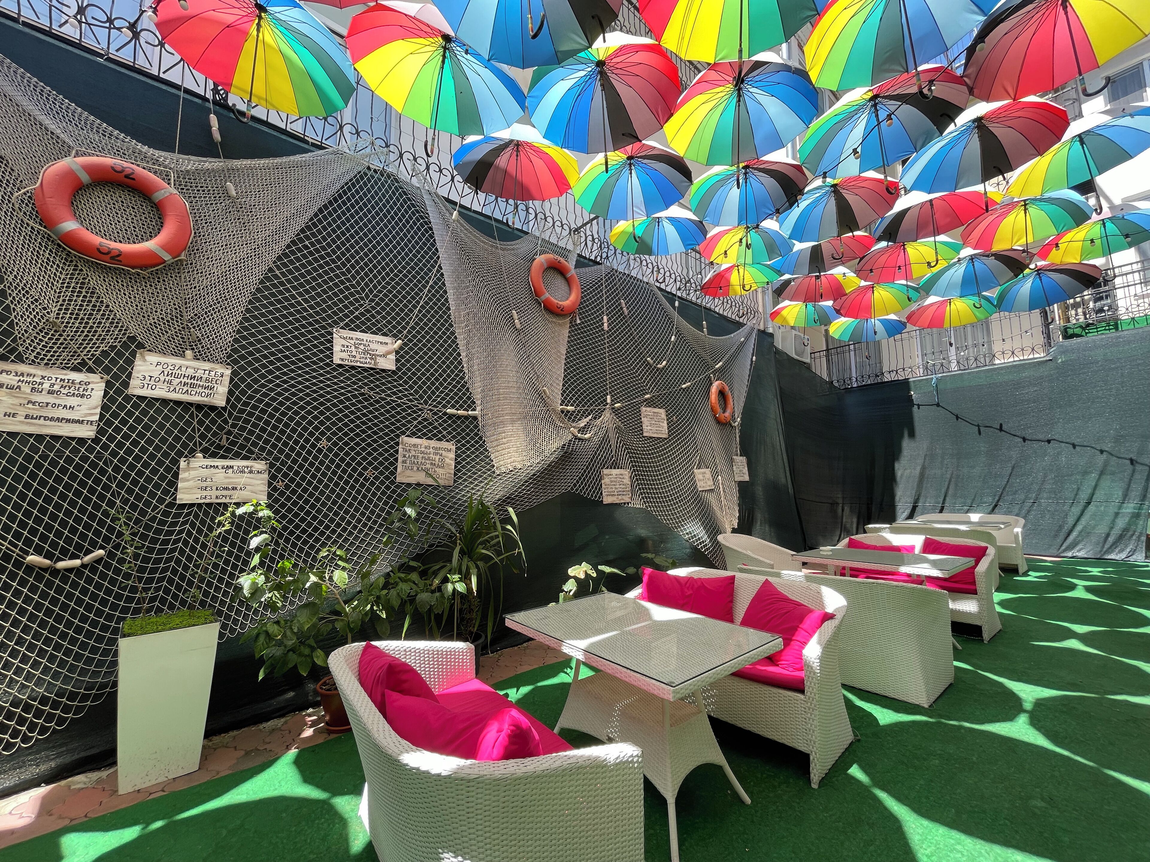 An outdoor seating area with wicker furniture and bright umbrellas overhead.