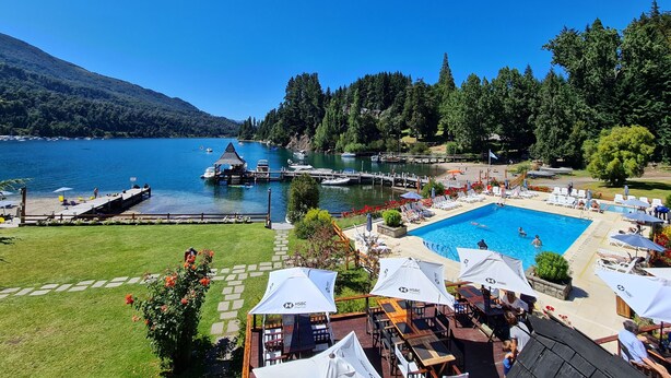 A lakeside resort with a swimming pool, docked boats, and a scenic mountain backdrop. - Bahia Manzano Resort (Villa La Angostura)