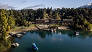 A lakeside hotel with multiple buildings, a dock with boats, and a forested mountain backdrop. - Bahia Manzano Resort (Villa La Angostura)