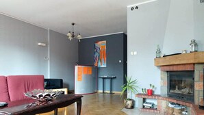 A living room with a fireplace, a sofa, a coffee table, and a wall with a colorful abstract painting. - Anton House (Warsaw)