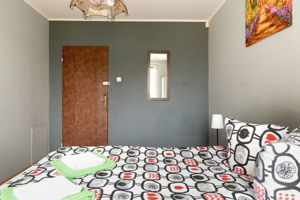 A bedroom with a bed, a door, a mirror, and a painting on the wall.