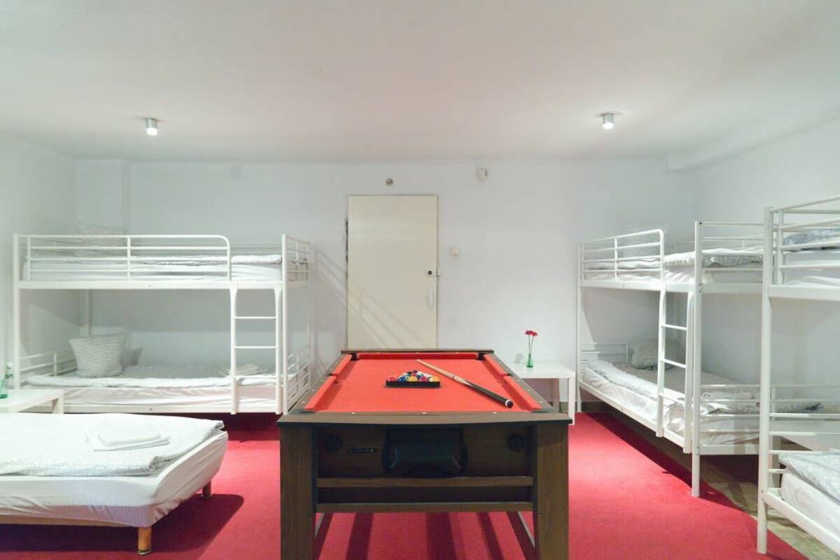 A room with bunk beds, a pool table, and a door.