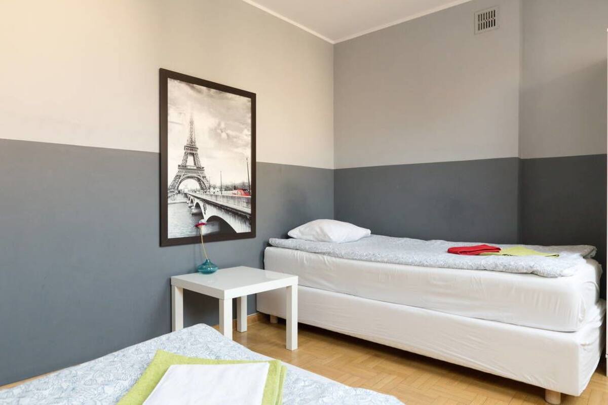 A hotel room with a bed, a small table, and a picture of the Eiffel Tower on the wall.