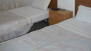 Habitación de hotel con dos camas individuales, una mesita de noche, una lámpara y un cuadro en la pared.