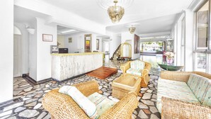 A spacious lobby with wicker furniture, a reception desk, and a staircase leading to upper floors. - Hotel Santa Barbara (Villavicencio)