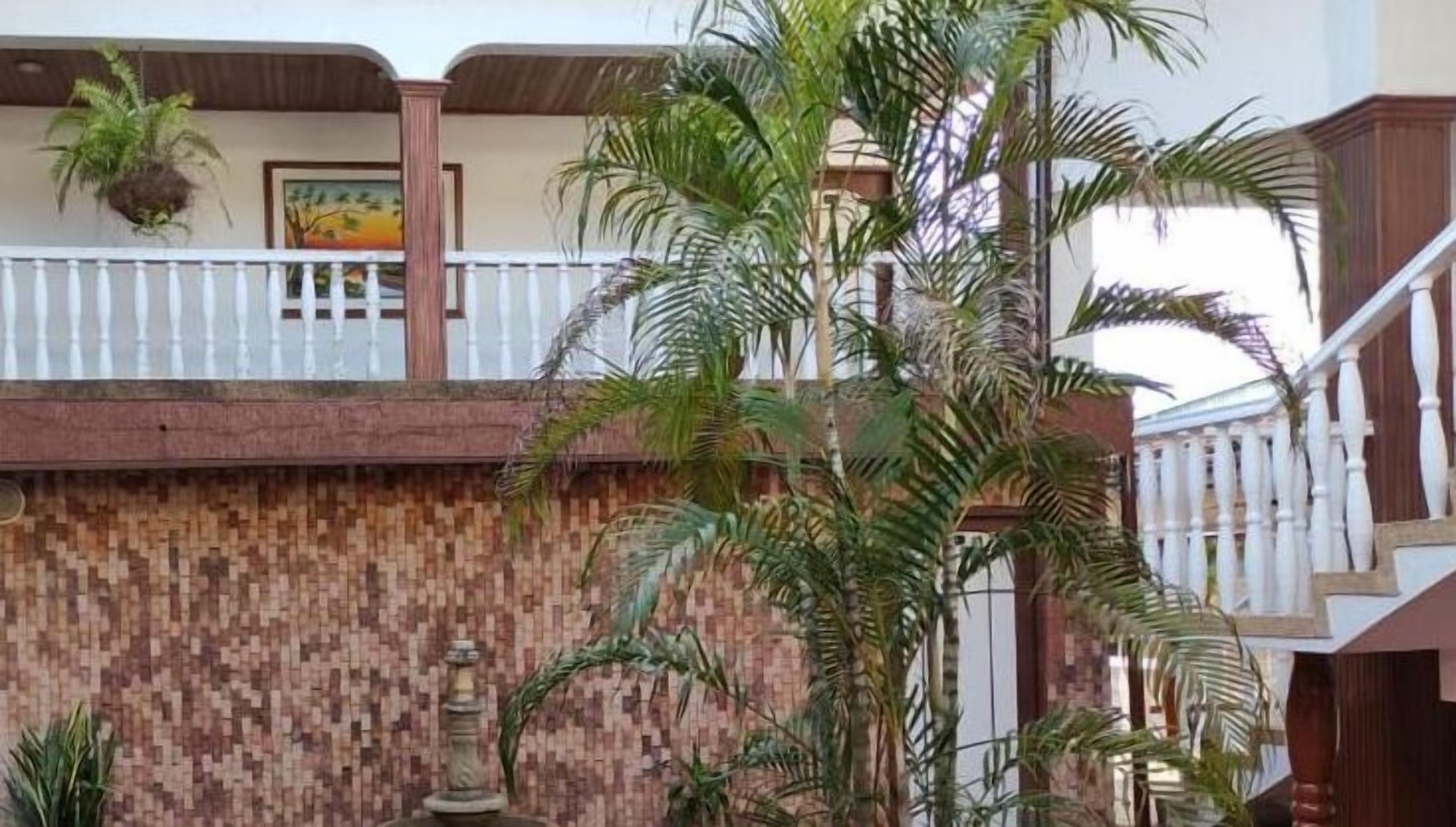 A building with a tiled wall, a balcony with a railing, and several potted plants.