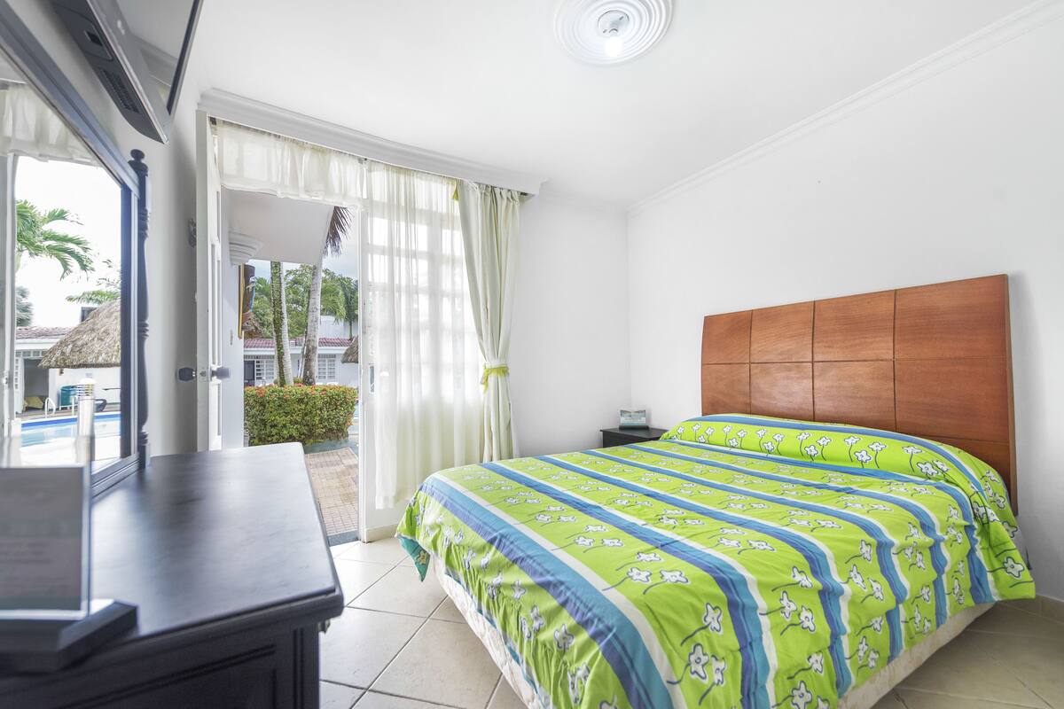 A hotel room with a bed, a desk, and a view of the outside.