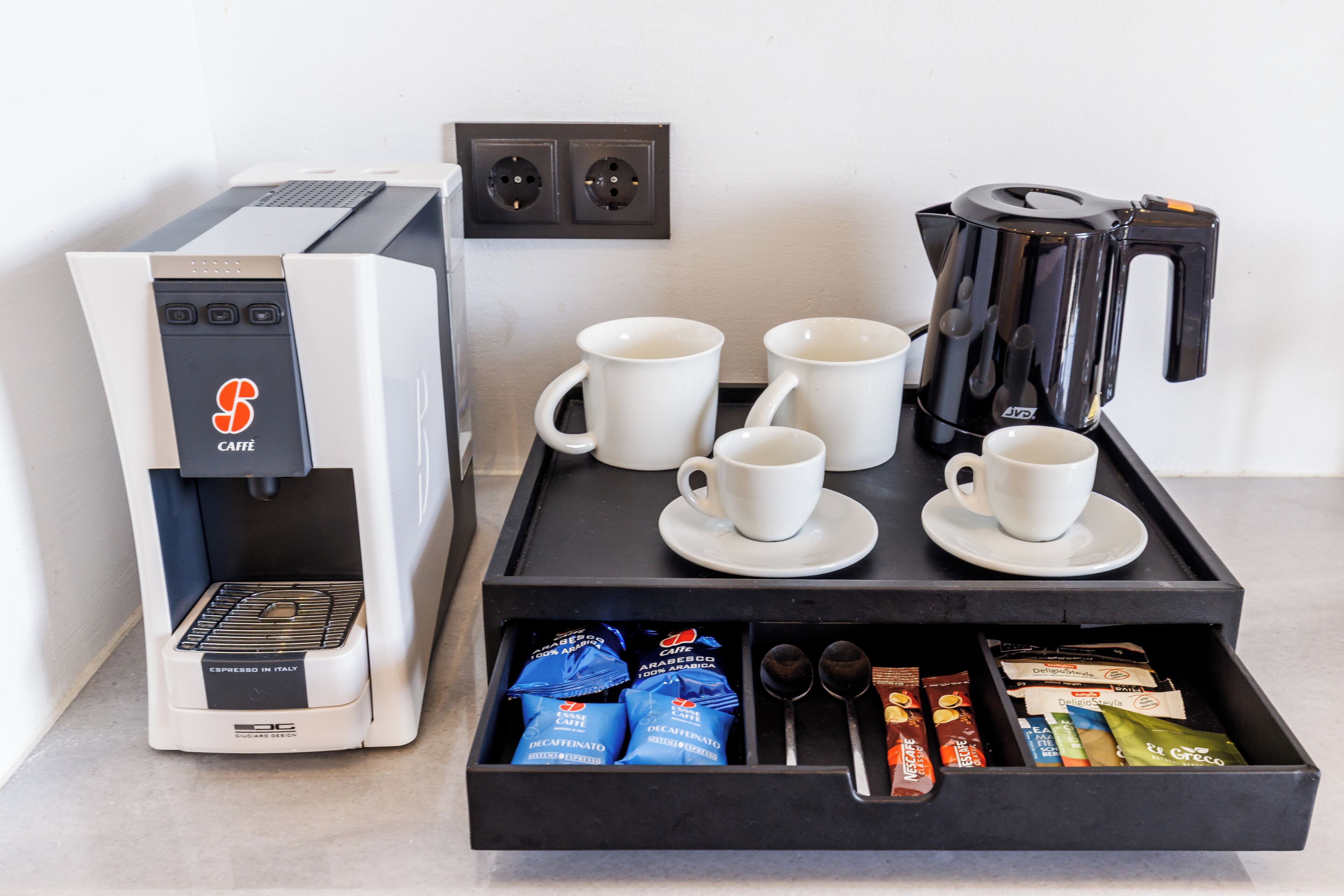 Een koffiehoek met een koffieapparaat, kopjes en koffiecups.